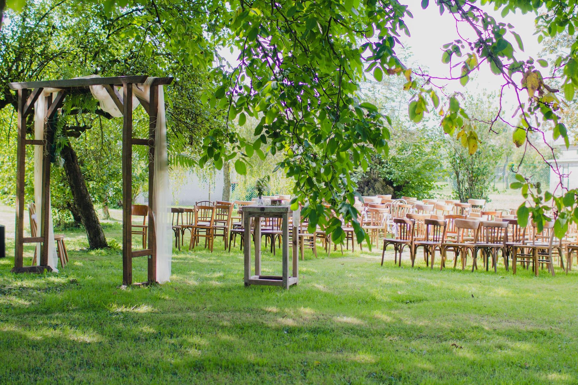 Cérémonie laïque dans un jardin : arche en bois et rangées de chaises