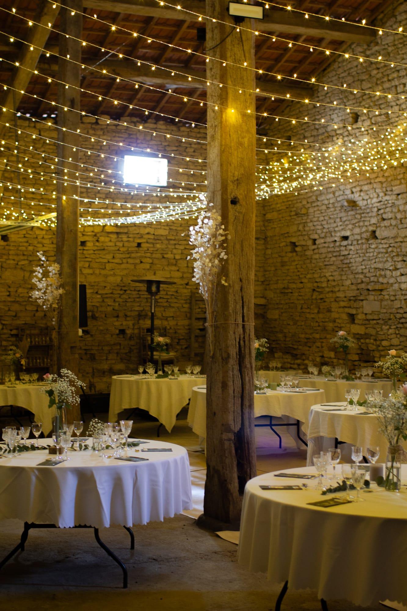 Stone barn lit with fairy lights, round tables dressed in white