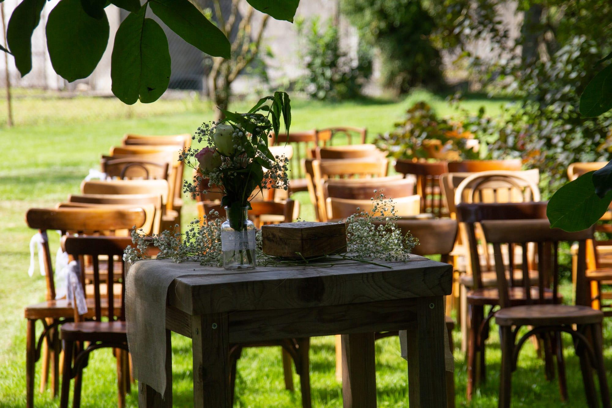 Flower-dressed ceremony table before rows of wooden chairs